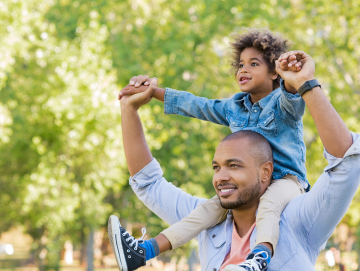 Son joyfully rides on his dad's shoulders because his dad completed an Oregon parenting class and experienced its positive impact.