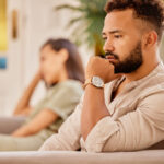 Man and woman sitting apart on a couch, reflecting the emotional strain of a high conflict divorce.