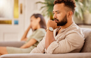 Man and woman sitting apart on a couch, reflecting the emotional strain of a high conflict divorce.