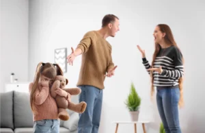 Parents arguing while the father gestures to their sad daughter holding a teddy bear, demonstrating co-parenting with a narcissist.