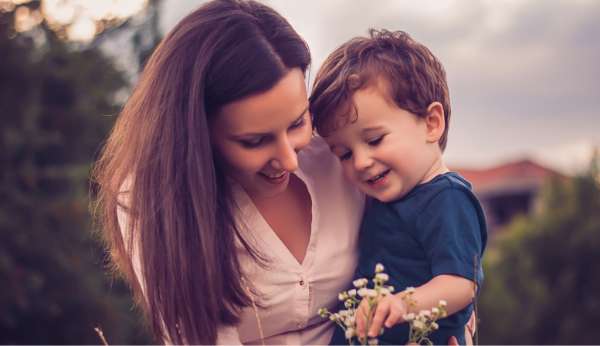 arizona-parenting-class A mother smiles with her son while he plays with flowers.