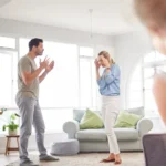 Parents arguing in the living room while a child observes.