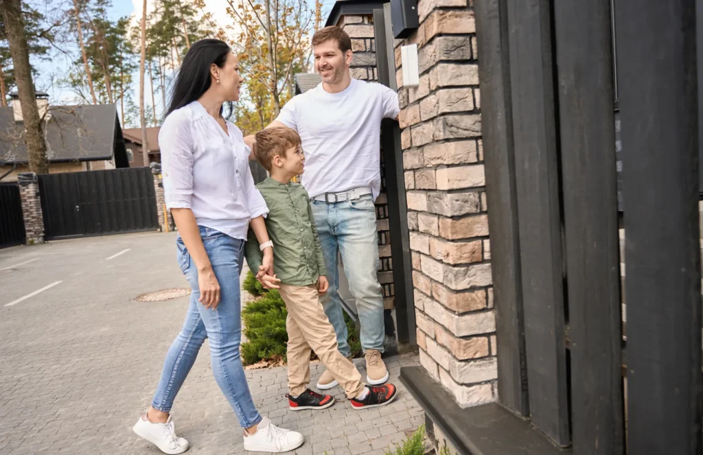 Parents and child happily greeting each other at a gate.