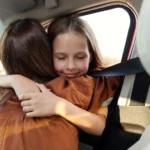 Parent and child hugging during a car exchange