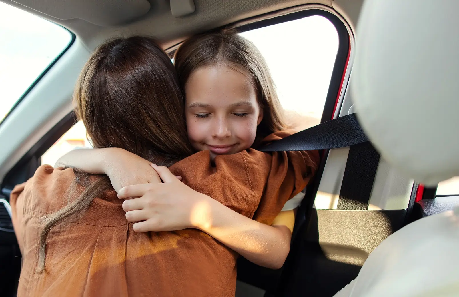 Parent and child hugging during a car exchange