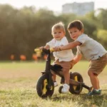 Two young brothers playing together outside on a balance bike on a sunny summer afternoon